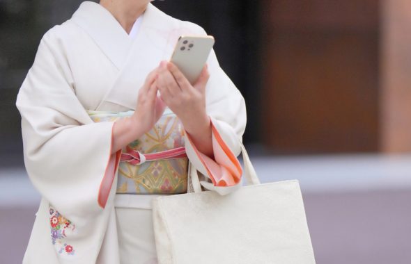 着物姿の女性がスマートフォンを操作する様子の画像