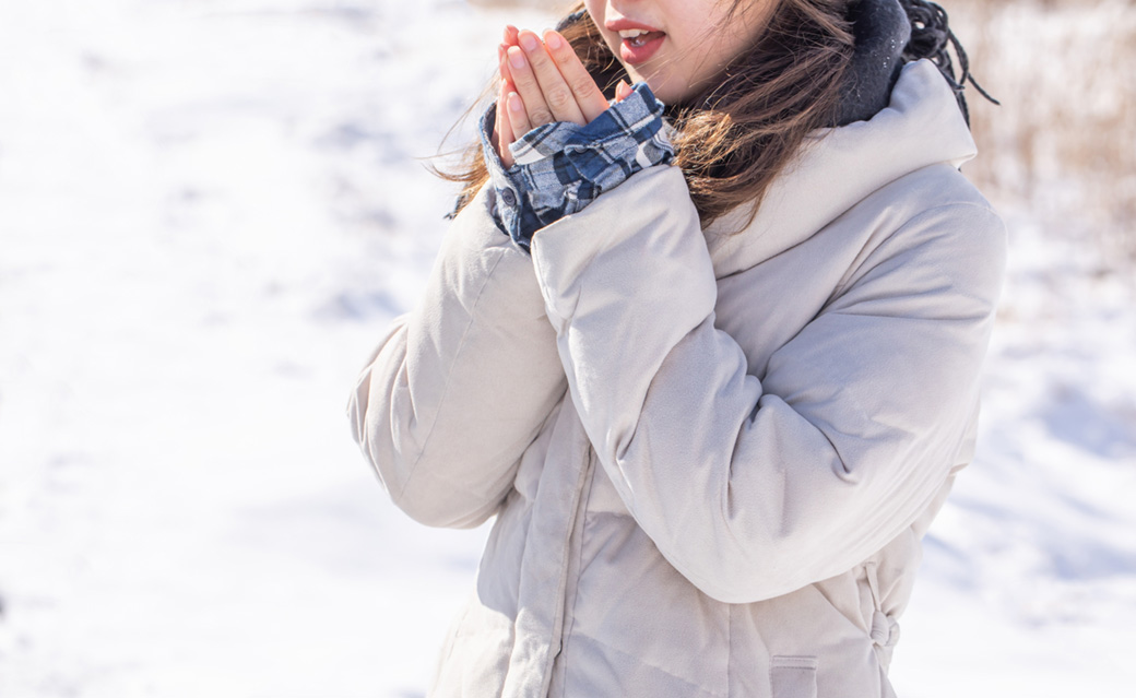 雪の中ダウンコートを着て寒い表情の女性の画像