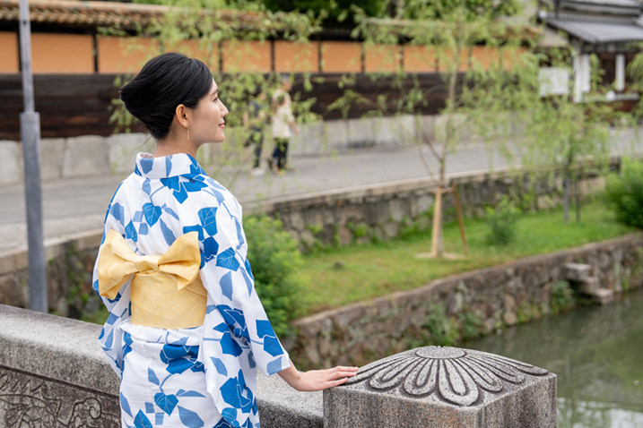 白地に青い花が散りばめられた浴衣を着て佇む女性の画像