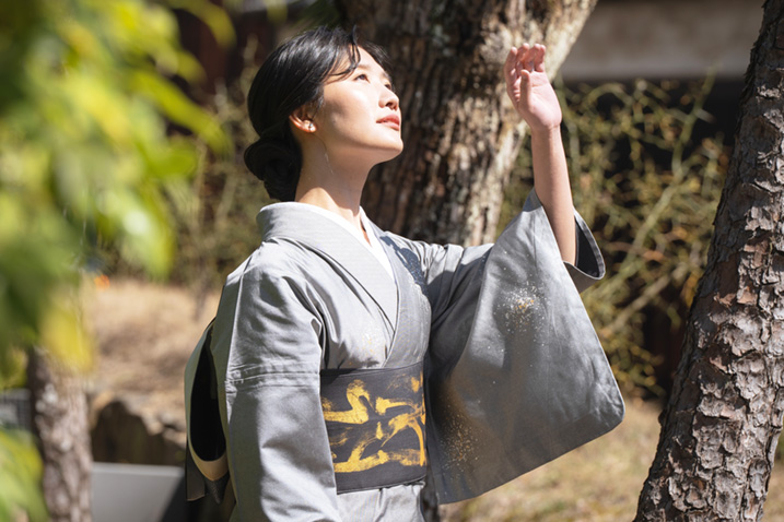 眩しい日差しを避ける様子の着物姿の女性の画像