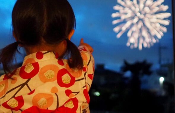 浴衣姿で花火を見学する子どもの画像
