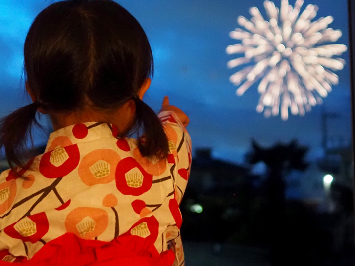浴衣姿で花火を見学する子どもの画像